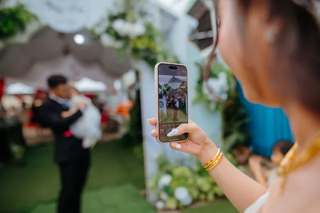A wedding guest photographing a scene from the celebration with a smartphone